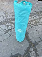 Play yard folded inside turquoise carry sleeve showing Regalo logo