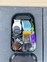 Clipper with cord and assorted colored guide combs inside storage case