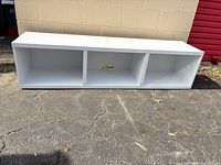 Front view of white three-cubby TV stand outdoors