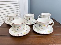 Five teacup and saucer sets displayed on table