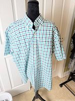 Front view of teal navy checked short-sleeve shirt on hanger