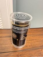 sealed clear plastic tube containing black fabric case with gold zipper