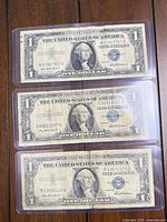 Three Series 1957 $1 silver certificates in sleeves