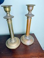 Both brass candlesticks standing on table