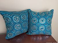 Front view of both teal sequin pillows showing circular sequin pattern