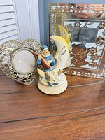 Group shot showing porcelain figurine, heart frame, silver baby frame