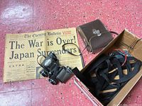 Binoculars, case, straps in box, 1945 newspaper headline visible