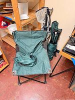 Green folding camp chair opened beside two bagged chairs