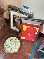 Clock and three framed prints grouped on floor