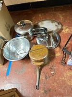 Group view of saucepan, steamer pieces, colander, splatter screen, lids