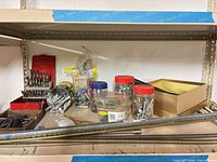 Shelf with drill bit sets, jars of screws, shelving rails and brackets