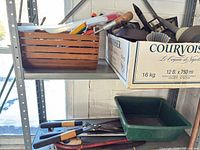 Shelf with wooden caddy, box of hand tools, soil sifter, hedge shears and bow saws visible
