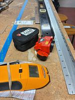 Overall view showing T-square, folding ruler segments, Black & Decker laser level with case, and stud finder