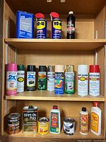Cabinet shelves with acetone, WD-40, spray paints, wood finishes visible