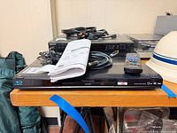 Top view of Blu-ray player with manual, remote and cable stacked