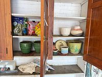 Cabinet shelves with multiple ceramic planters and potting mix bags