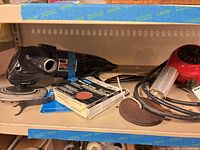 Shelf with Craftsman grinder-polisher, Norton disc box, red heat gun, loose disc