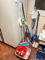 Group of cleaning tools including Shark steam mop, broom, dustpan, buckets