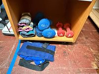 Overall view of dumbbells and strap weights inside shelf and on floor