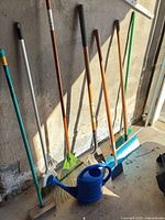 Group shot of all long-handled tools and watering can leaning against wall