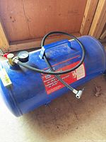 Full view of blue Campbell Hausfeld 7 gallon air tank with hose and gauge