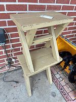 two stacked beige painted wood benches against brick wall