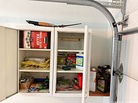 Open wall cabinet with chemicals, rope, tools visible