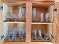 Cabinet view showing brandy glasses, frosted flutes, cylindrical highballs, faceted tumblers