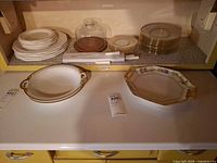 Overall lot showing plates, trays, cheese dome and glass plates on shelf