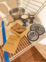 Shelf view showing oil lamp box, Britannia bowl, two goblets, two plates