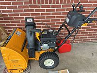 Left side view of Cub Cadet 524 snow blower showing controls, engine, headlight and included red gas can