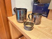 Two handled cups and napkin ring on wooden surface