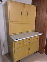 Front view of complete yellow cabinet showing upper and lower sections, enamel surface, chrome hardware