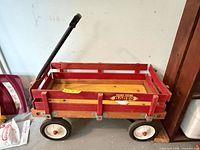 Side view of Radio Flyer Rodeo wagon showing red wooden slats, yellow deck, black handle, white wheels