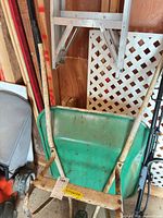 Wheelbarrow front and ladder folded against wall
