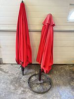 Two folded red umbrellas beside black metal stand