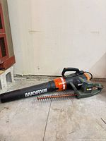 Worx Turbine 600 leaf blower and Black & Decker hedge trimmer side by side on floor