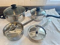 Overview of four of the stainless steel pots with lids