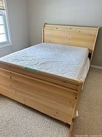 Full view of pine sleigh bed frame with mattress and bedding