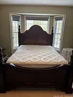 Full view of assembled solid wood queen bed with mattress in bay window setting
