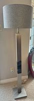 Full view of brushed metal floor lamp with shade and base