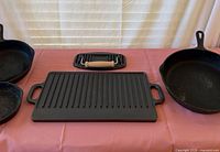 Overall view showing griddle, press, large skillet right, medium skillet left, small skillet lower left