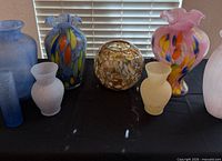 Eight assorted art glass vases on table