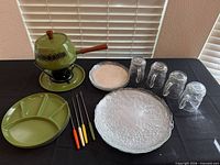 full set on table: fondue pot on stand with drip plate, sectioned plate, forks, two textured glass plates, four glass mugs