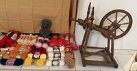 Spinning wheel beside grouped yarn skeins on floor