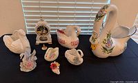 Group shot of all swan ceramics, mantel clock and key on table