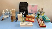 Overall view of entire lot on table showing soaps, perfumes, scale, grooming kit and décor items