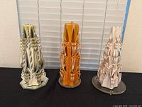 Three carved ribbon candles side by side showing overall condition and colors