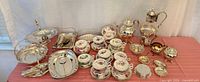Full lot showing teacups, saucers, silverplate kettle, teapot, serving pieces, utensils
