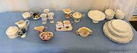 Overview of dinnerware, creamers, sugar bowls, bud vases on table